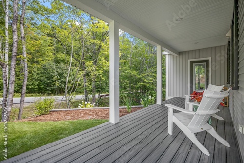 Beautiful gray porch of a modern custom new England colonial home with a garden photo