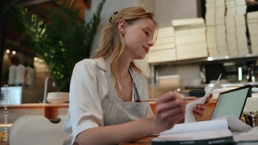 Positive blonde woman waitress writing something in notepad in the cafe Positive blonde woman waitress writing something in notepad in the cafe