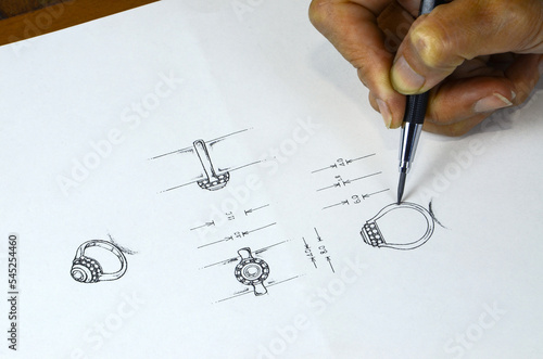Jewelry design drawing On paper, draw a detailed diamond ring jewelry sketch on the top and side of the actual size of the jewelry. along with drawing tools and creative metal rings Design Studio.
