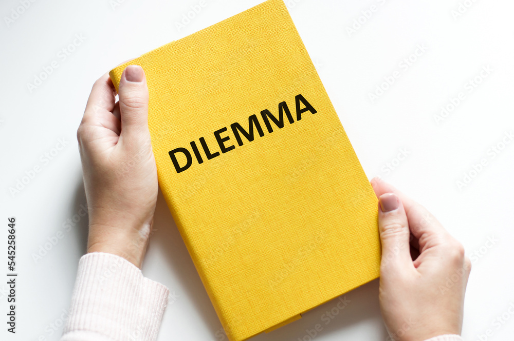 DILEMMA inscription on a yellow notebook on a light background in the hands of a person, a business concept DILEMMA inscription on a yellow notebook on a light background in the hands of a person, a business concept