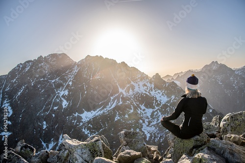Beautiful blonde woman enjoys reaching the summit in the Slovak Tatras and looks at the Gerlach mountain. Mala Wysoka peak in the Tatra Mountains at sunset. High Tatras, Slovakia