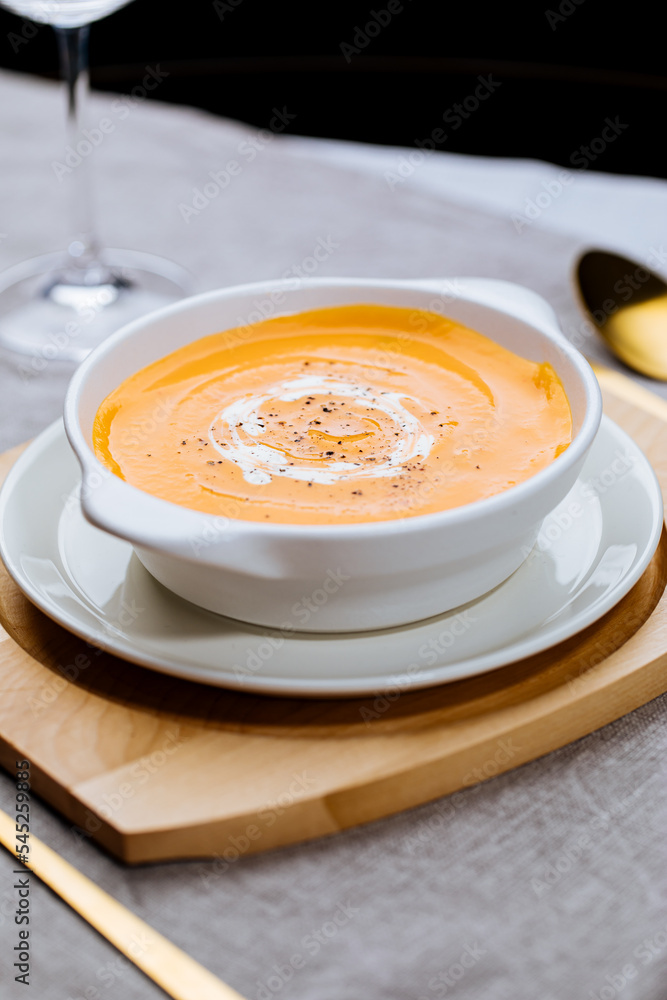 Creamy pumpkin soup garnished with cooking sauce served in turquoise dish with slice of bread in rustic mood. Seasonal warm food. Autumn Appetiser Creamy pumpkin soup garnished with cooking sauce served in turquoise dish with slice of bread in rustic mood. Seasonal warm food. Autumn Appetiser