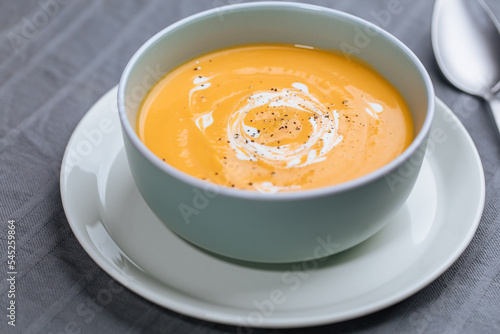 Creamy pumpkin soup garnished with  cooking sauce served in turquoise dish with slice of bread in rustic mood. Seasonal warm food. Autumn Appetiser 