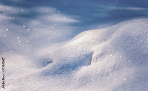 Christmas background with snow. White snowy hills in winter. Shadows on the snow. Wide panoramic format. Natural wallpaper for design.
