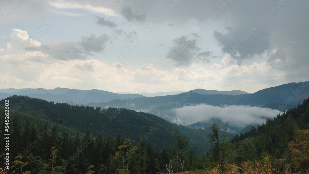 Summer and autumn hiking in the Carpathian mountains, stunning views from the tops, blue cloudy sky, fog