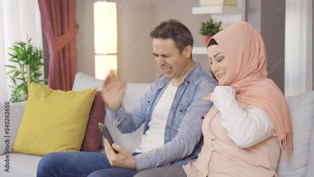 Muslim woman in hijab and her husband looking at the phone together at home.
Muslim family laughing, looking at the phone and having fun.
Muslim woman in hijab and her husband looking at the phone together at home.
Muslim family laughing, looking at the phone and having fun.