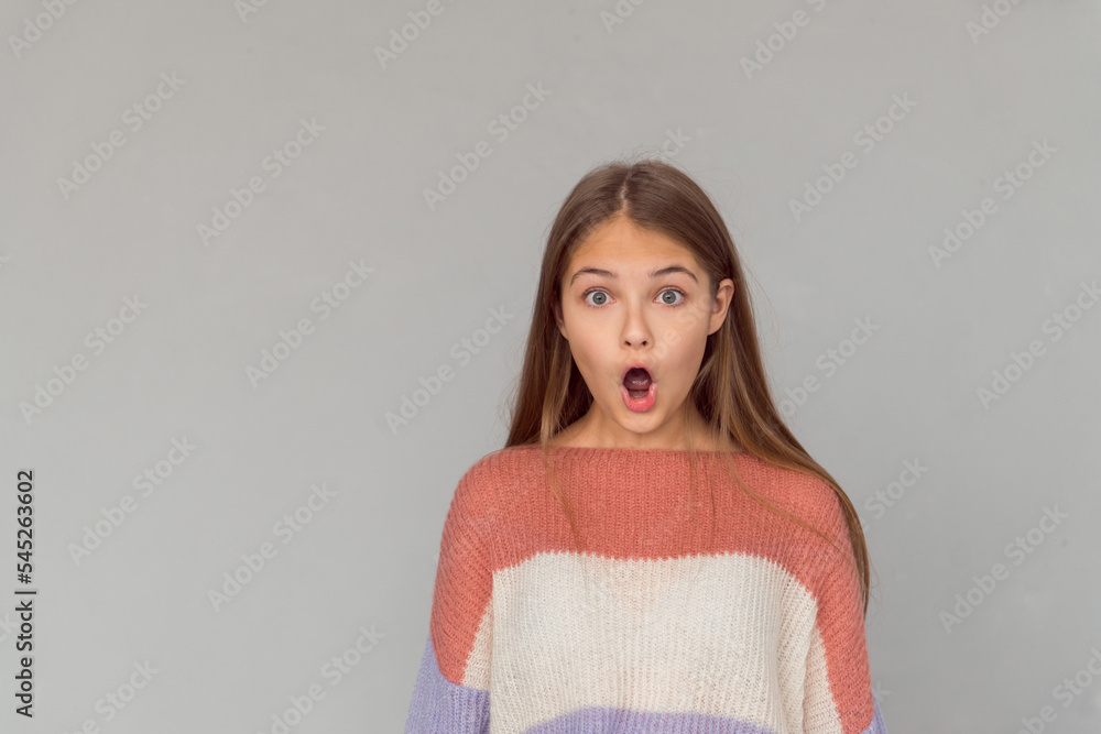 Emotional portrait of young girl open mouth surprised face isolated on gray background Emotional portrait of young girl open mouth surprised face isolated on gray background