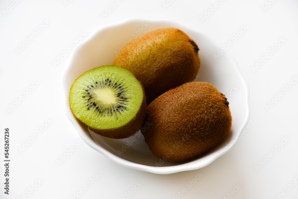 Fresh and juicy kiwi fruit, chopped and whole on a white plate. Delicious fruits and pieces of green kiwi. Fresh and juicy kiwi fruit, chopped and whole on a white plate. Delicious fruits and pieces of green kiwi.