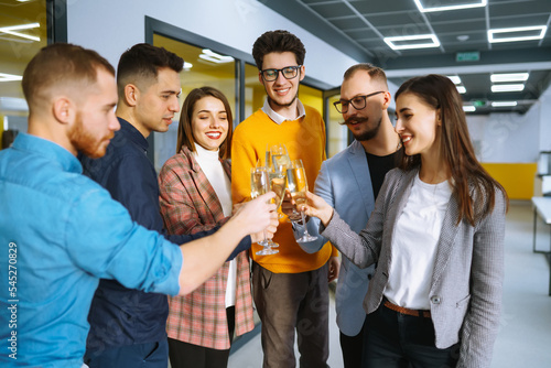 Toasting to success concept.Group of young business people toasting each other and smiling while standing in the office. Celebration and festive concept.