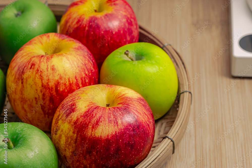 red and green apples isolated in wicker basket with wooden background red and green apples isolated in wicker basket with wooden background