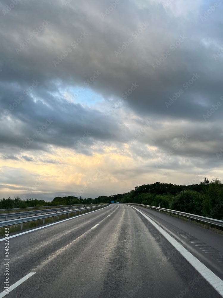 Empty highway in the fields, stormy sky