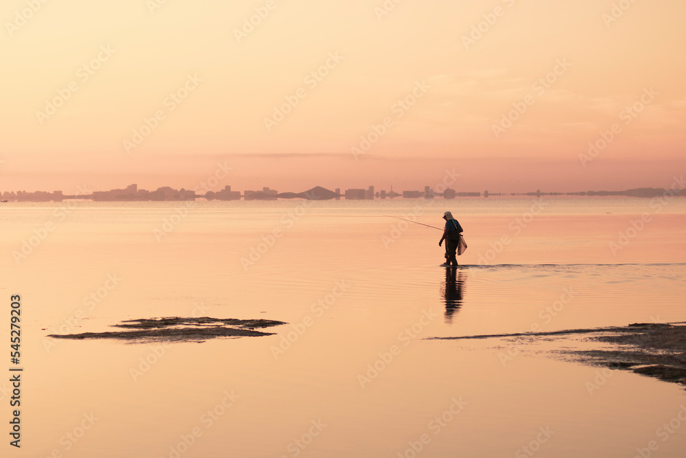Traditional fisherman fishing with a rod at sunrise in the Mar Menor, Region of Murcia, Spain