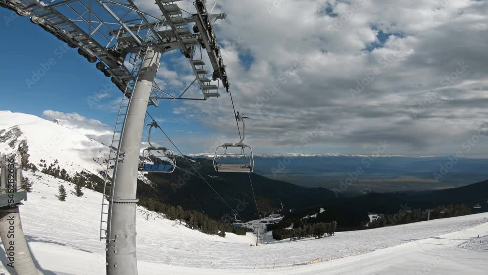 Empty ski lift on mountain ski slope in Bansko, Bulgaria on sunny day with bright blue sky Empty ski lift on mountain ski slope in Bansko, Bulgaria on sunny day with bright blue sky