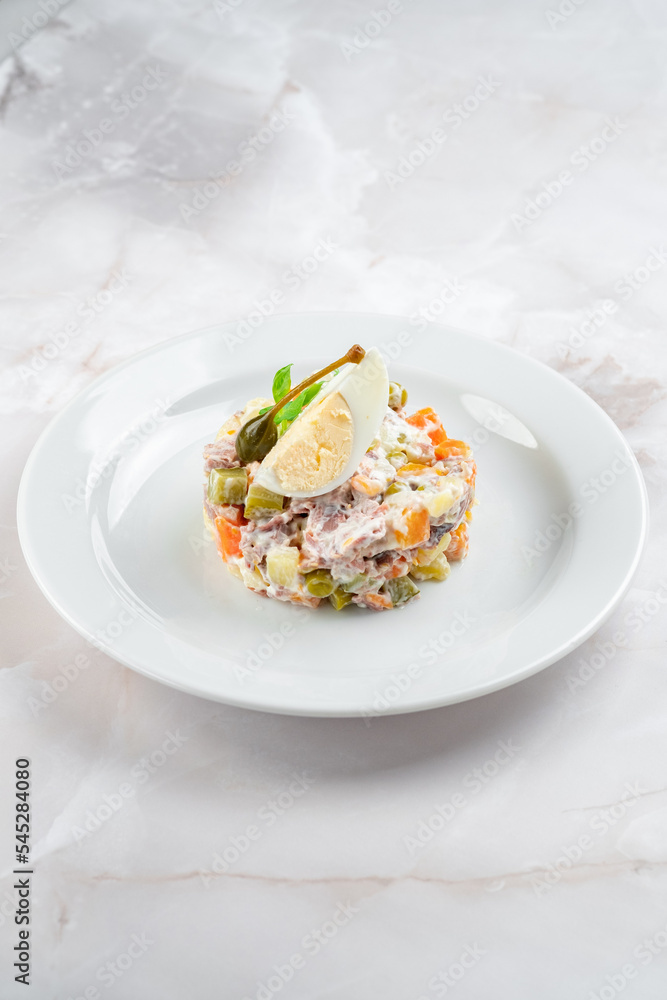 Russian salad olivier decorated dish on a white plate. Hearty salad of potatoes, carrots, peas, egg, cucumbers and mayonnaise Russian salad olivier decorated dish on a white plate. Hearty salad of potatoes, carrots, peas, egg, cucumbers and mayonnaise