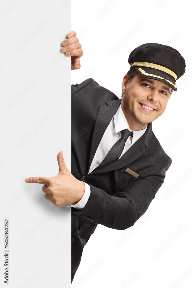 Smiling bellboy standing behind a white panel and pointing Smiling bellboy standing behind a white panel and pointing