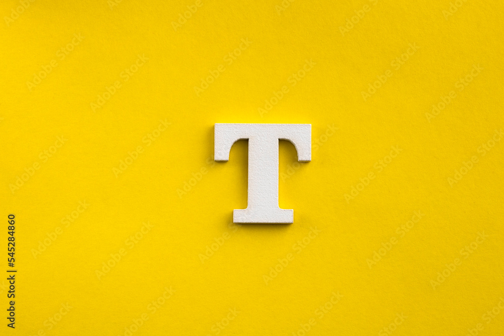 Obraz premium Alphabet letter T - White wood letter on yellow colored background