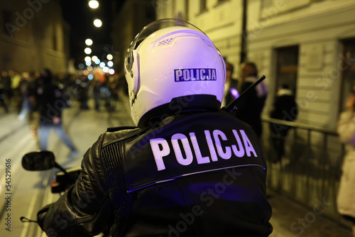 Policjant wydziału ruchu drogowego z motocyklem podczas kontroli miasta wieczorem.  Światła policyjne.