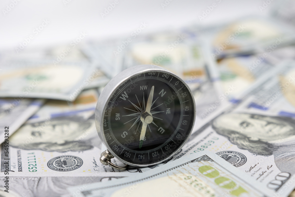 Classic navigational compass on the background of one hundred dollar bills Classic navigational compass on the background of one hundred dollar bills