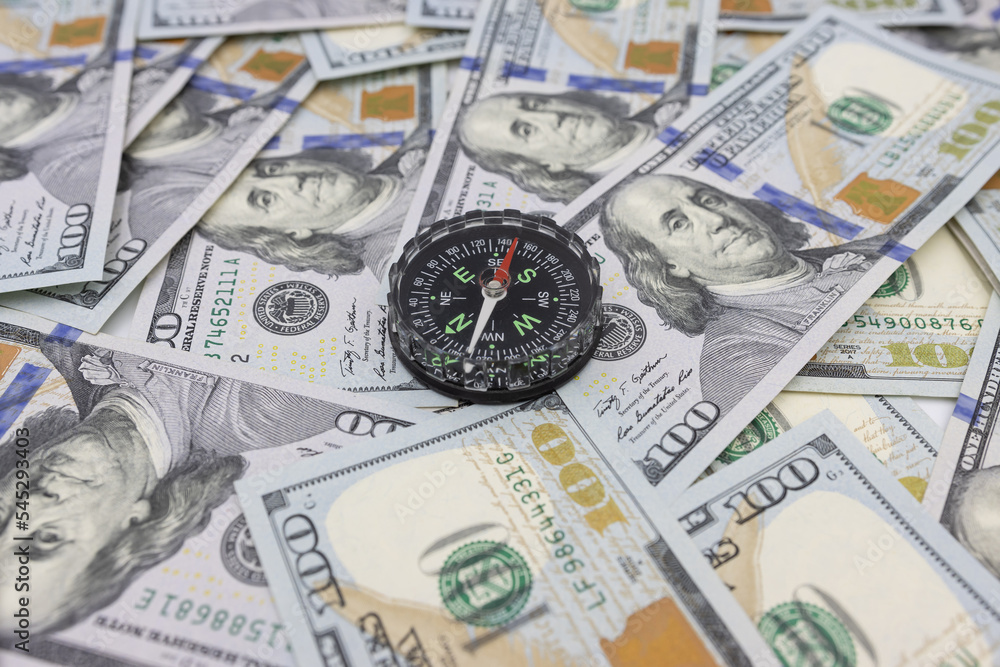 Classic navigational compass on the background of one hundred dollar bills Classic navigational compass on the background of one hundred dollar bills