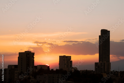 cloudy yellow orange and pink sunset, framed by city buildings