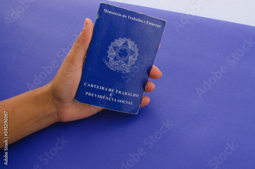 Ministry of Labor and Employment. National Work Card of Brazil. Brazilian notebook. Concept of CLT, INSS, FGTS, unemployment, salary and Brazilian economy. Hand holding a Brazilian work card. photo