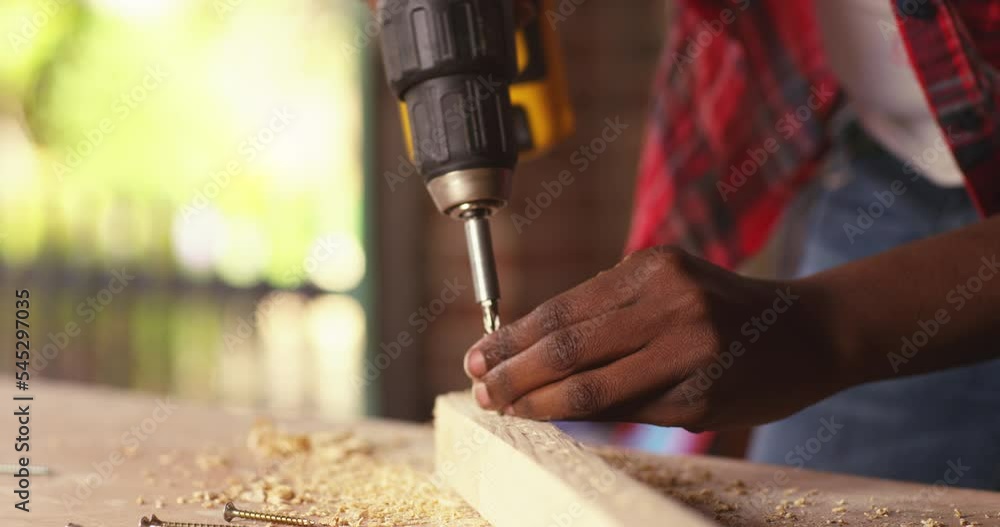 Young woman using a screwdriver on a piece of wood while working in a workshop Young woman using a screwdriver on a piece of wood while working in a workshop