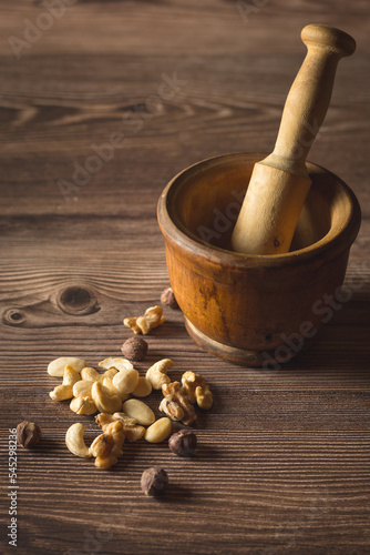 Différentes variétés de fruits à coques et mortier et pilon en bois en arrière-plan