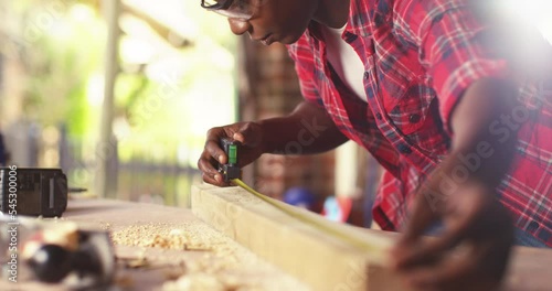 Female craftsmen use tape measure to assemble wooden pieces