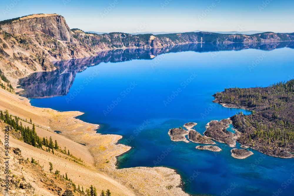 View of Crater Lake with mirror-like reflections on a calm and clear summer morning.