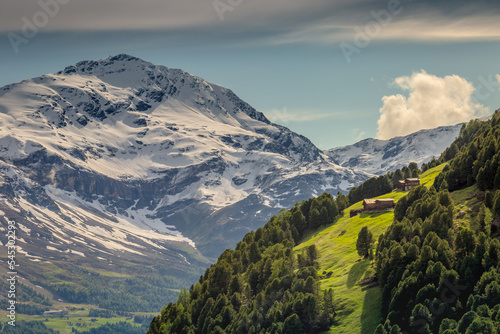 Snowcapped mountains in Stelvio national park with farms, Valfurva, Italian alps