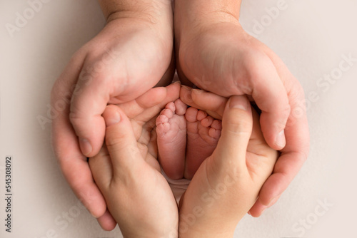 Children's foot in the hands of mother, father, parents. Feet of a tiny newborn close up. Little baby legs. Mom and her child. Happy family concept. Beautiful concept image of motherhood stock photo