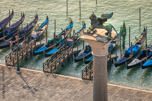 Gondole docked by wooden mooring poles in grand canal, Ethereal Venice, Italy