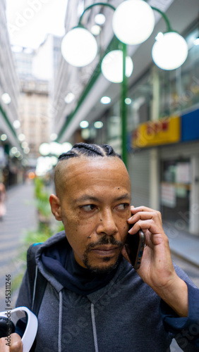 black man talks on cellphone and listens to music on an afternoon in the city