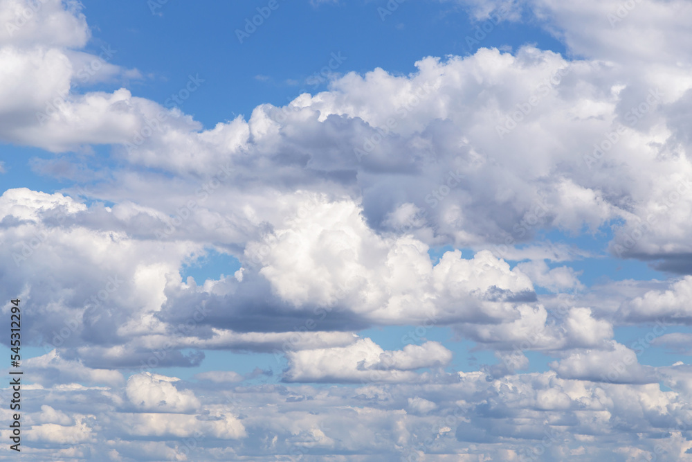 Blue cloudy sky with many beautiful white fluffy cumulus clouds in sunlight background texture Blue cloudy sky with many beautiful white fluffy cumulus clouds in sunlight background texture