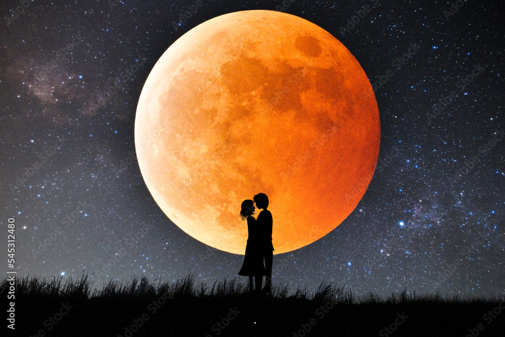 皆既月食で赤く染まった月をバックにキスするカップルのシルエット。
