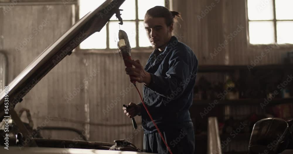 Male mechanic turning off flashlight Male mechanic turning off flashlight