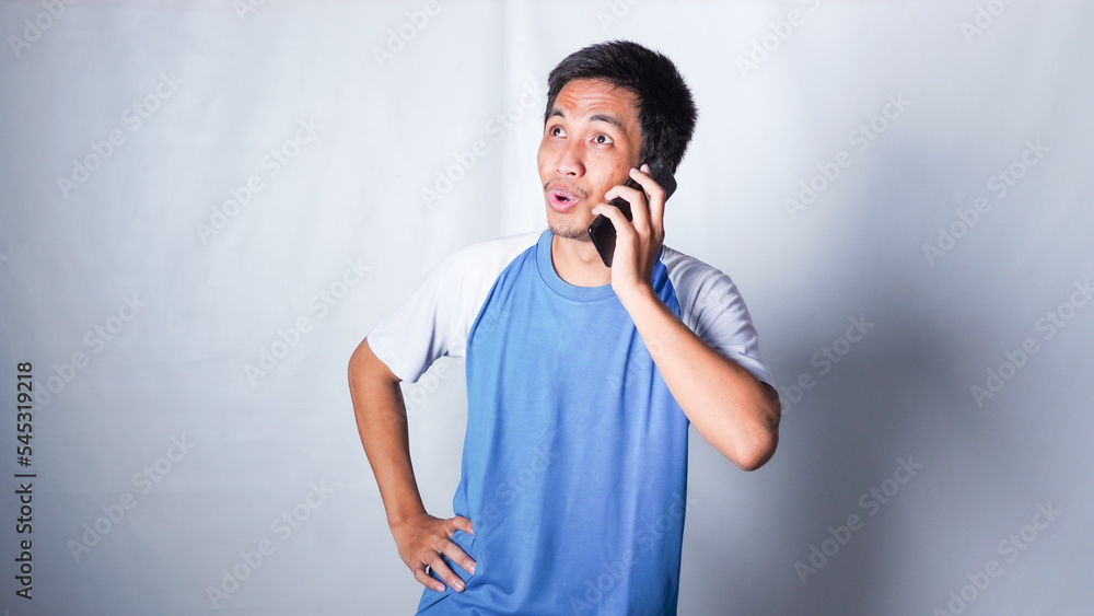 asian man wearing blue shirt answer call with smile and get an idea asian man wearing blue shirt answer call with smile and get an idea