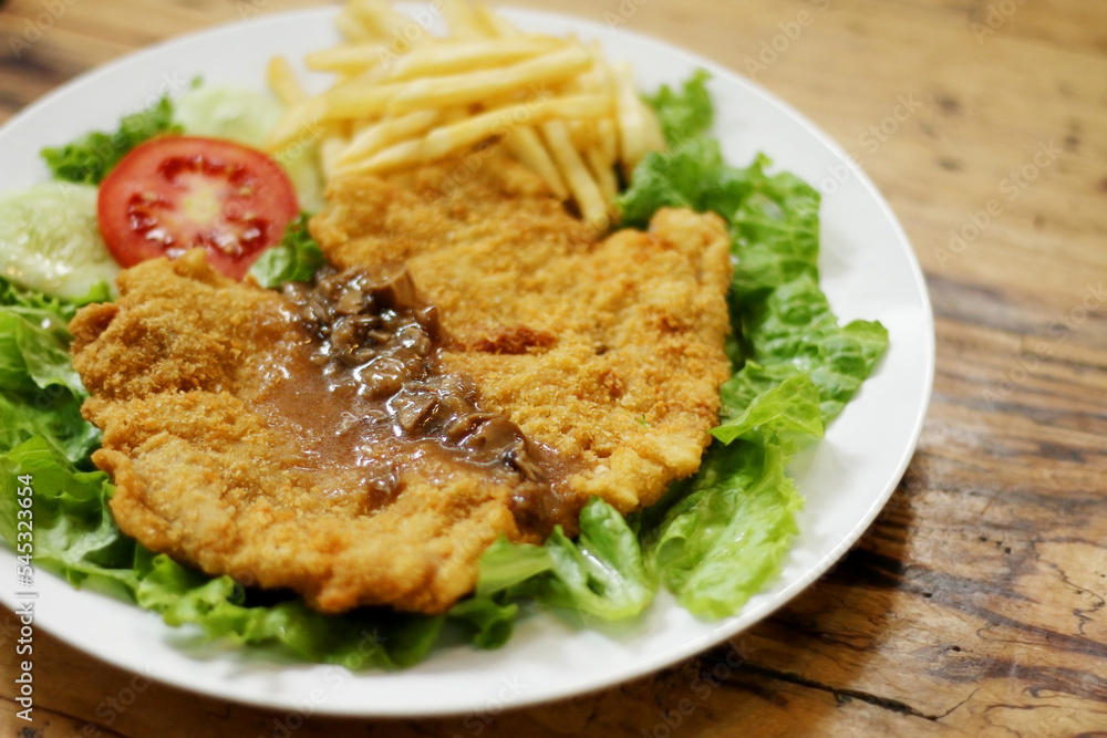 Chicken schnitzel served with mushroom sauce, french fries, lettuce, cucumber and tomato pieces Chicken schnitzel served with mushroom sauce, french fries, lettuce, cucumber and tomato pieces
