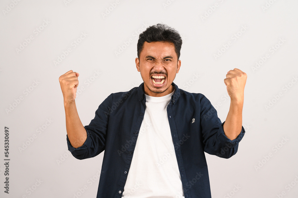 Portrait of Happy young asian man in blue shirt excited doing winner gesture with arm raised isolated on white background Portrait of Happy young asian man in blue shirt excited doing winner gesture with arm raised isolated on white background