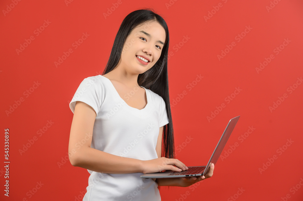 Portrait of a happy asian businesswoman working on laptop computer isolated over red background Portrait of a happy asian businesswoman working on laptop computer isolated over red background
