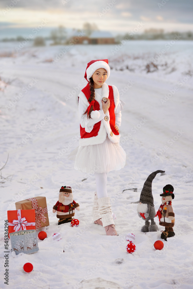 Obraz premium A girl in a New Year's costume with gifts from Santa Claus, not on the street.