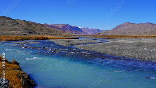 curved azure blue river through mountain peaks, autumn valley landscape