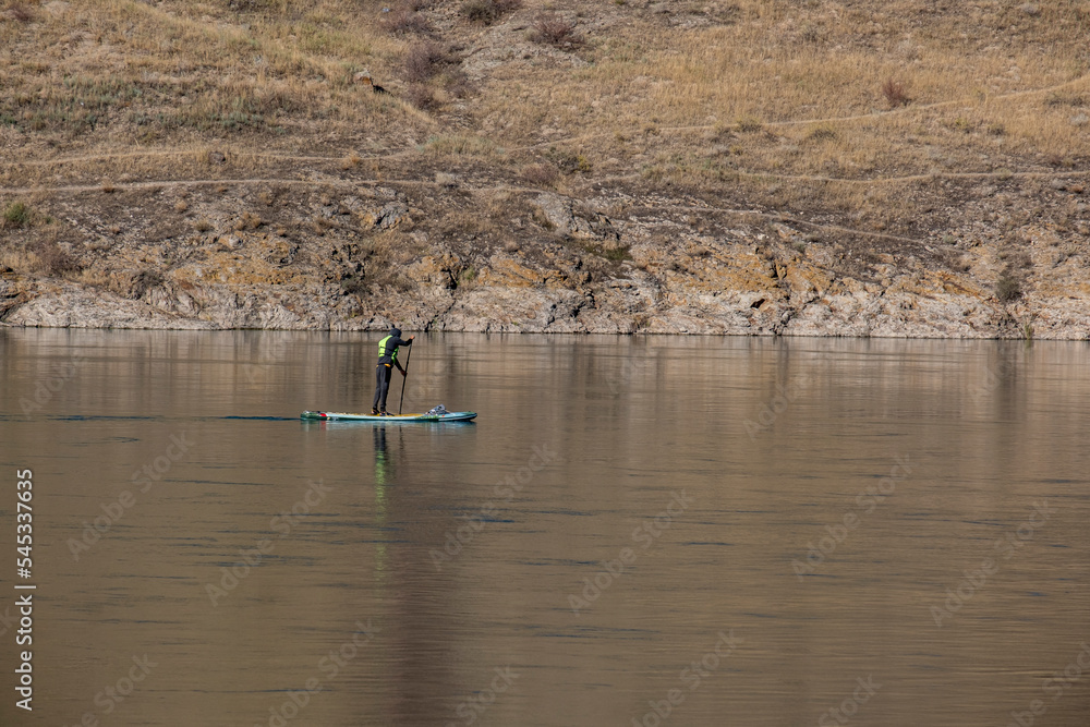 A man on a Subboard is rafting down a river. Active water sport.
