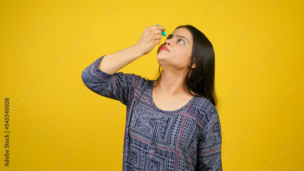Young woman using eye drops isolated over yellow background, eye dropper or eyes drop concept Young woman using eye drops isolated over yellow background, eye dropper or eyes drop concept