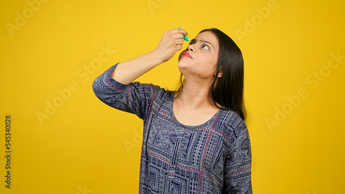 Young woman using eye drops isolated over yellow background, eye dropper or eyes drop concept