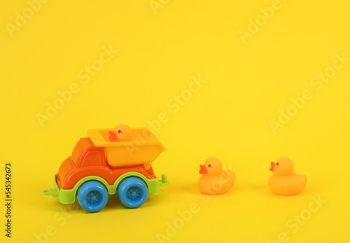 Fotografie Toy dump truck with rubber little ducklings on a yellow background
