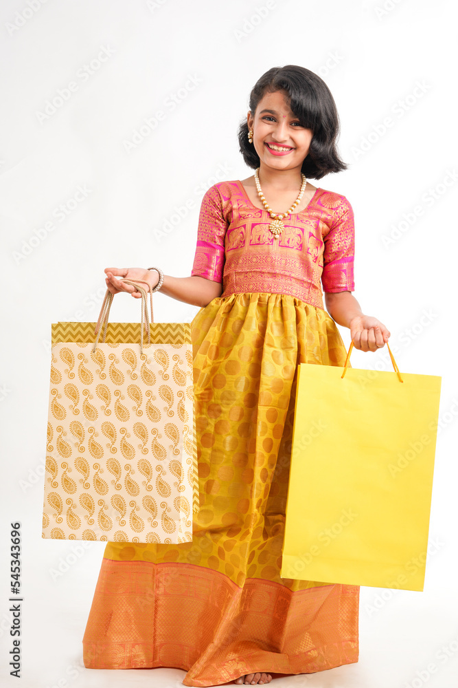Happy Indian little girl holding shopping bags on white background. Happy Indian little girl holding shopping bags on white background.