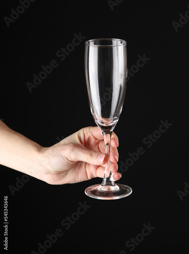 Woman's hand holding an empty glass of champagne on a black background