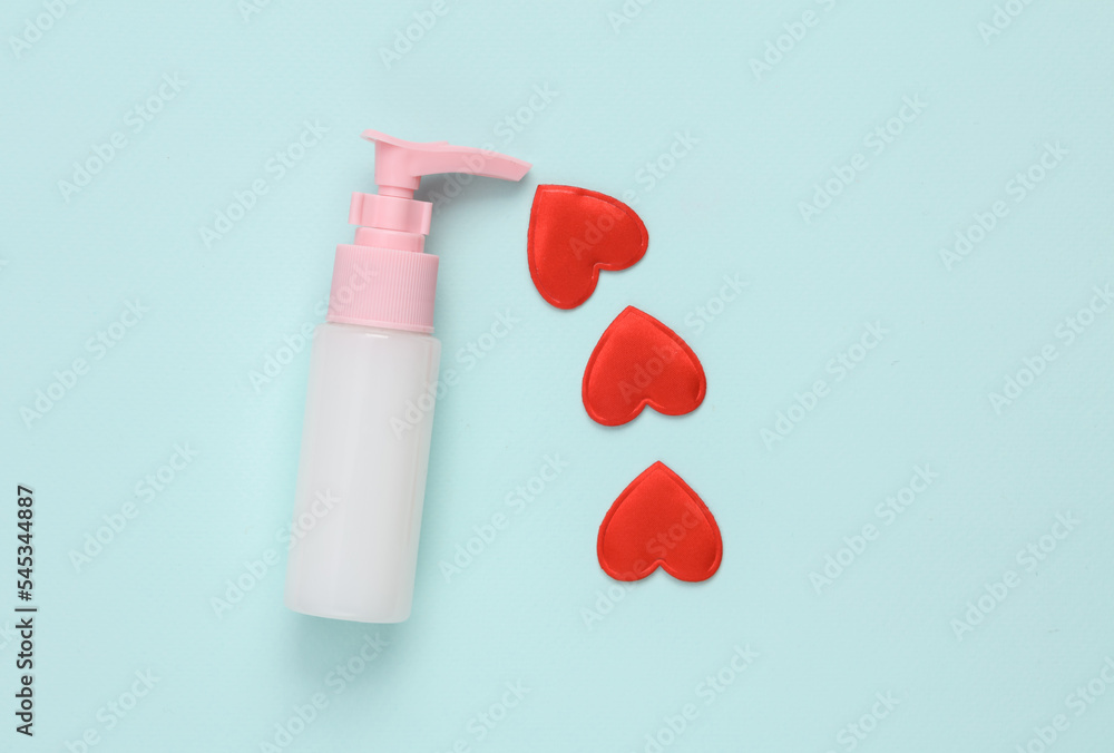 Bottle of liquid milk or cream and a heart on a blue background. Beauty, love concept Bottle of liquid milk or cream and a heart on a blue background. Beauty, love concept