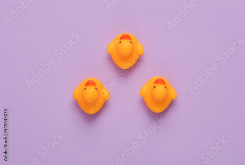 Rubber ducklings on purple background. Top view